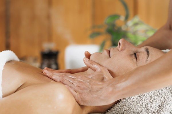 Woman enjoying professional Ayurveda neck and shoulders massage with ethereal oil